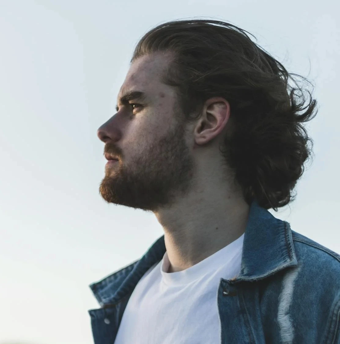 Photo de profil d'une jeune homme avec une barbe et des longs cheveux